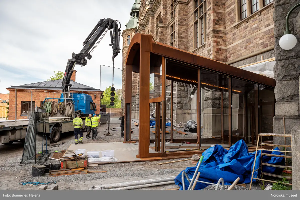 Exteriörer från Nordiska museets västra sida, bakgården, under arbetet med den nya entrén och byggnaden Lusknäppen. Entrén är ritad av Lone-Pia Bach. Konstnären Outi Pieski står för den konstnärliga gestaltningen med konstverket Two Directions, inspirerat av föremål ur museets samiska samlingar. Montering av glaset i utbyggnaden.