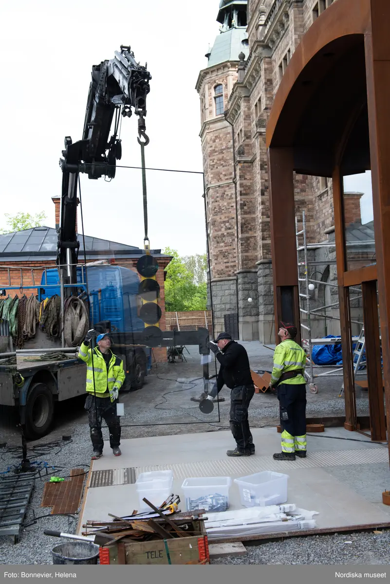 Exteriörer från Nordiska museets västra sida, bakgården, under arbetet med den nya entrén och byggnaden Lusknäppen. Entrén är ritad av Lone-Pia Bach. Konstnären Outi Pieski står för den konstnärliga gestaltningen med konstverket Two Directions, inspirerat av föremål ur museets samiska samlingar. Montering av glaset i utbyggnaden.