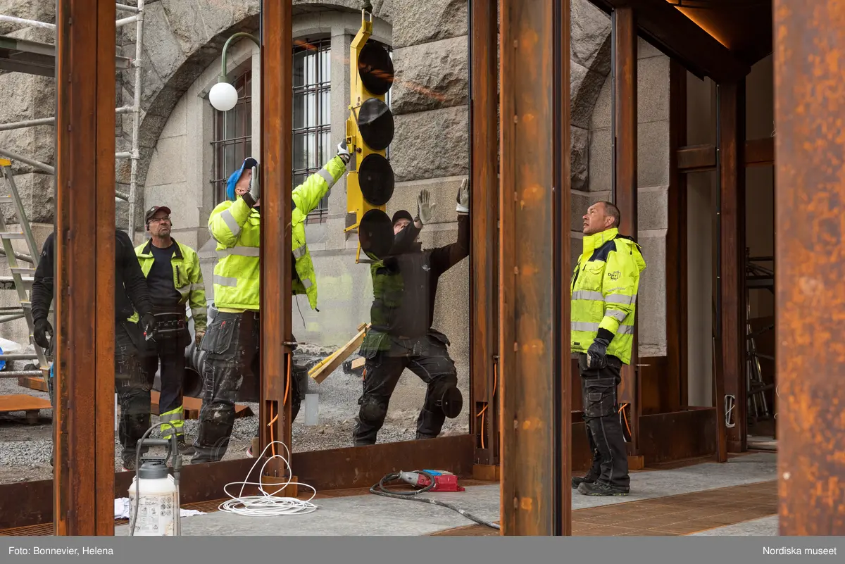 Exteriörer från Nordiska museets västra sida, bakgården, under arbetet med den nya entrén och byggnaden Lusknäppen. Entrén är ritad av Lone-Pia Bach. Konstnären Outi Pieski står för den konstnärliga gestaltningen med konstverket Two Directions, inspirerat av föremål ur museets samiska samlingar. Montering av glaset i utbyggnaden.