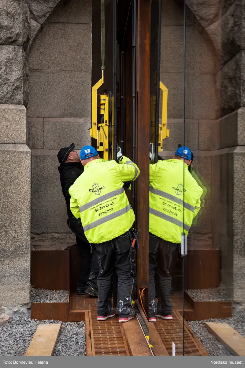 Exteriörer från Nordiska museets västra sida, bakgården, under arbetet med den nya entrén och byggnaden Lusknäppen. Entrén är ritad av Lone-Pia Bach. Konstnären Outi Pieski står för den konstnärliga gestaltningen med konstverket Two Directions, inspirerat av föremål ur museets samiska samlingar. Montering av glaset i utbyggnaden.