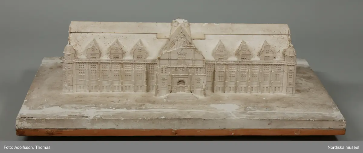 Huvudliggaren:
"Byggnad, modell; Nordiska museets hallbyggnad, gips; trol.gjord för erhållande av byggnadstillstånd; mycket skadad . Från 1891, funnen omärkt på vinden."