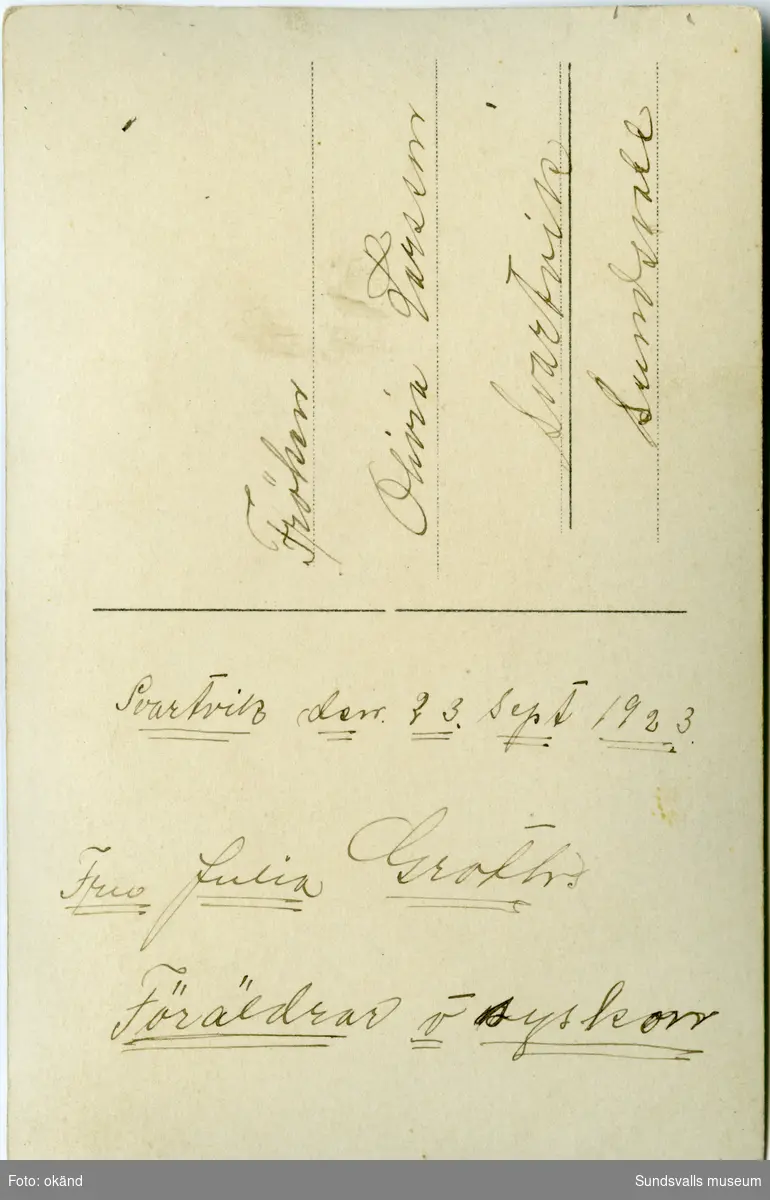 Vykort med en gruppbild på brokvisten till ett trähus, 14 personer. På baksidan står: "Svartvik den 23 sept 1923. Fru Julia Groths föräldrar och syskon." Ur en samling som tillhört Olivia Larsson, Svartvik.