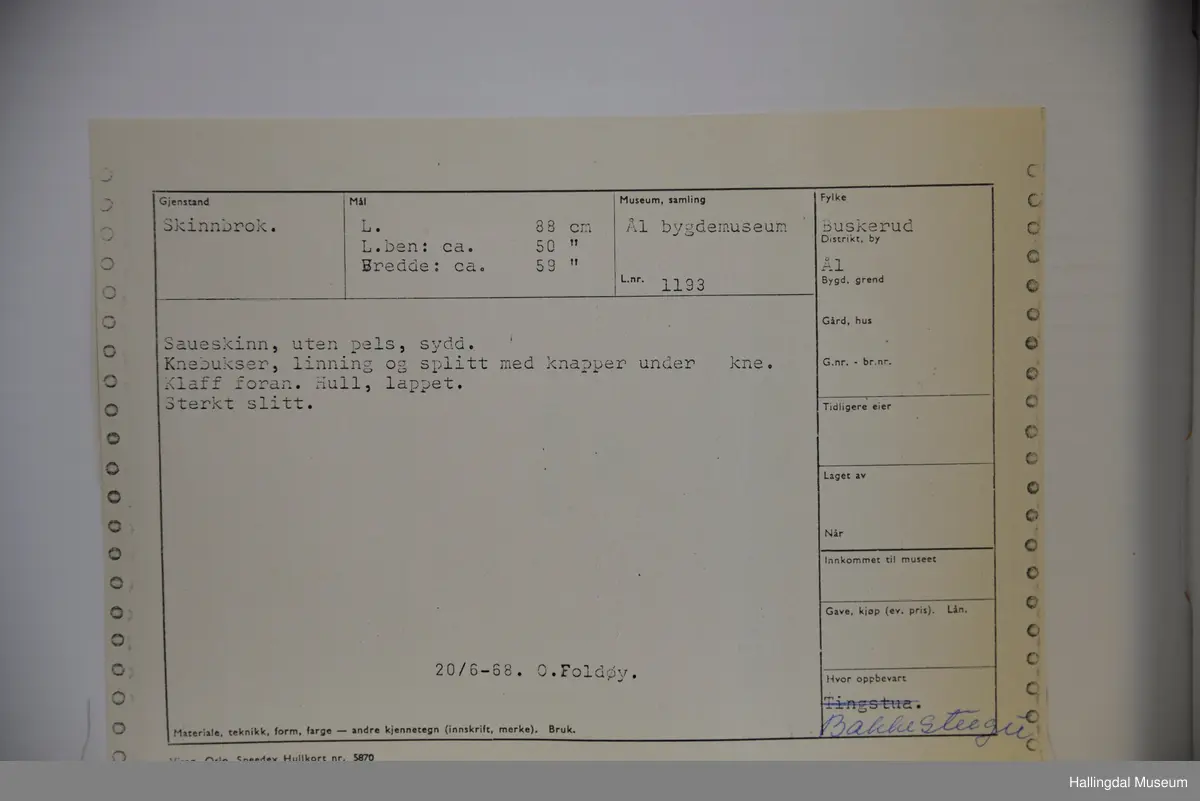 Saueskinn, uten pels, håndsydd. Klaff foran. Linning og splitt med knapper under kne. Knebukser,  Hull lappet. Slitt.