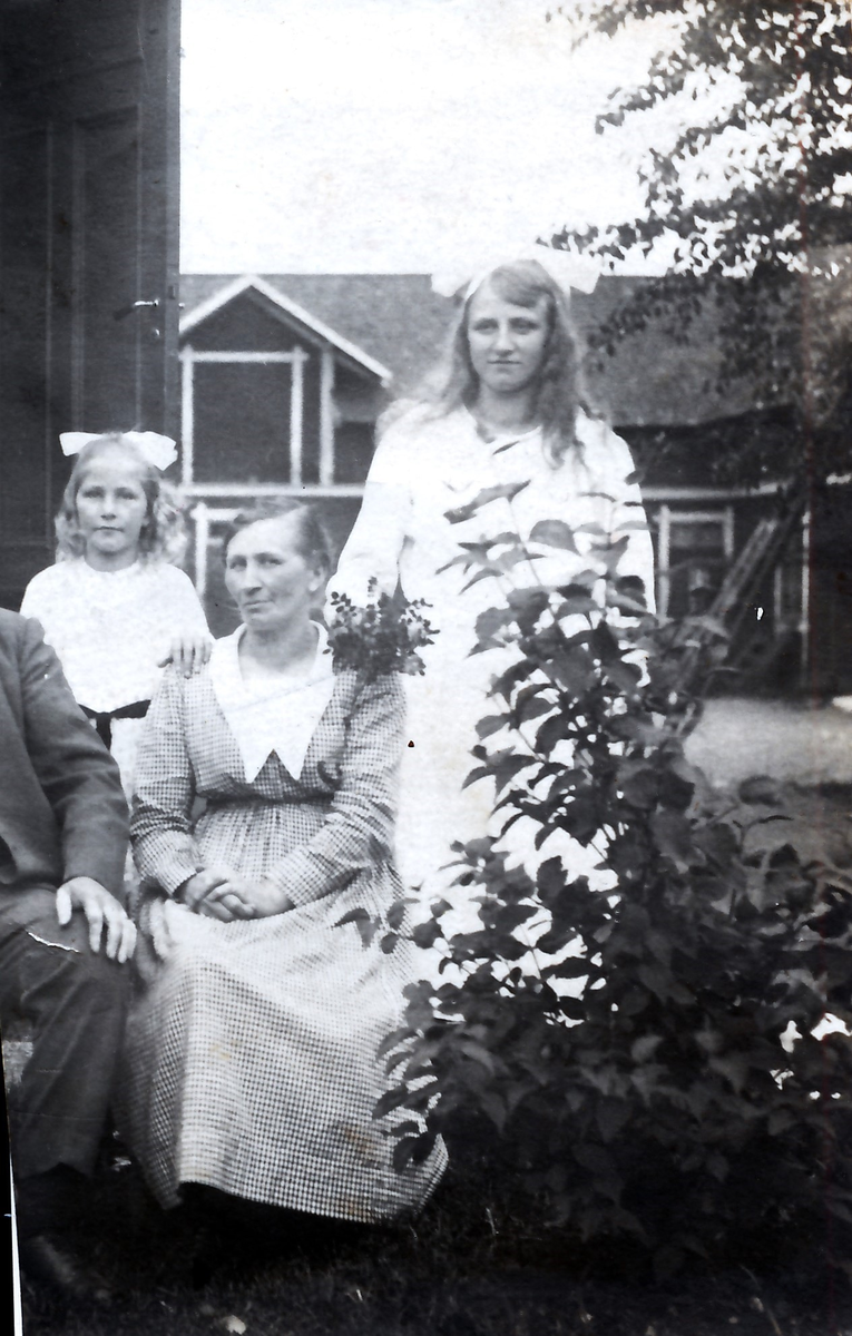 Ituklippt vykort med familjefotografi taget på okänd plats, alltså inte på Kustsanatoriet. Bild 1 och 2 visar de olika delarna och bild 3 den sammansatta bilden. Vykortet är adresserat till Elin Andersson på Kustsanatoriet Apelviken 3 från storasystern Maja i Röjeråsen, avsänt 1921, så möjligen är fotot taget där. Merparten av mannen som sitter med det minsta barnet i knät är bortklippt. De sitter i trädgården invid ett bostadshus, där dörren på gaveln står öppen. I bakgrunden ligger ytterligare ett hus.