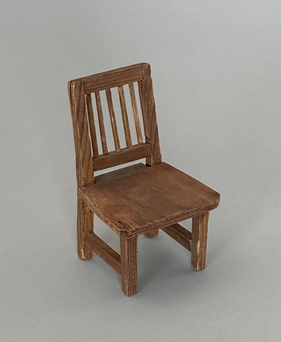 Brunbetsad leksaksstol i trä och plywood.