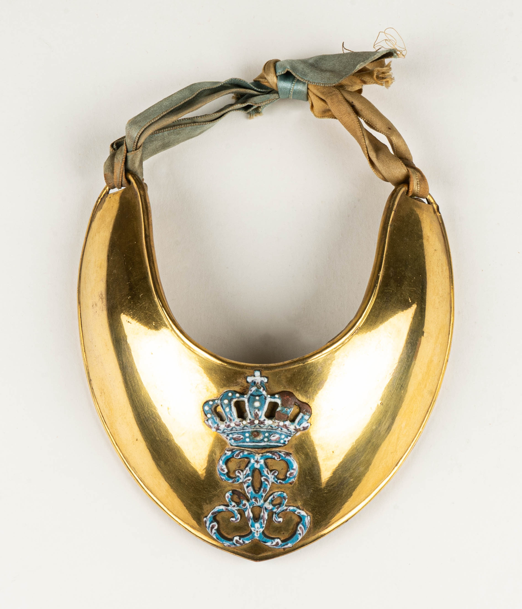 Dagofficersbricka, förgylld. Har tillhört kapten Th. Nordenadler, Högbo, Gästrikland.  Med Gustav III:s namnchiffer i ljusblå emalj. Dagofficersbrickan ingår i Gustav III:s uniform m/1779, för kaptener / kompanichefer för infanteriet.