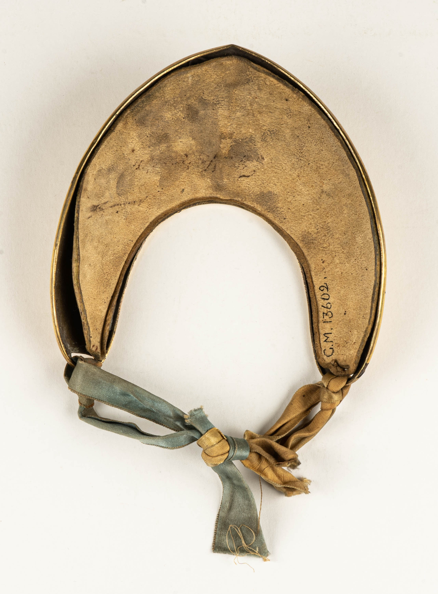 Dagofficersbricka, förgylld. Har tillhört kapten Th. Nordenadler, Högbo, Gästrikland.  Med Gustav III:s namnchiffer i ljusblå emalj. Dagofficersbrickan ingår i Gustav III:s uniform m/1779, för kaptener / kompanichefer för infanteriet.