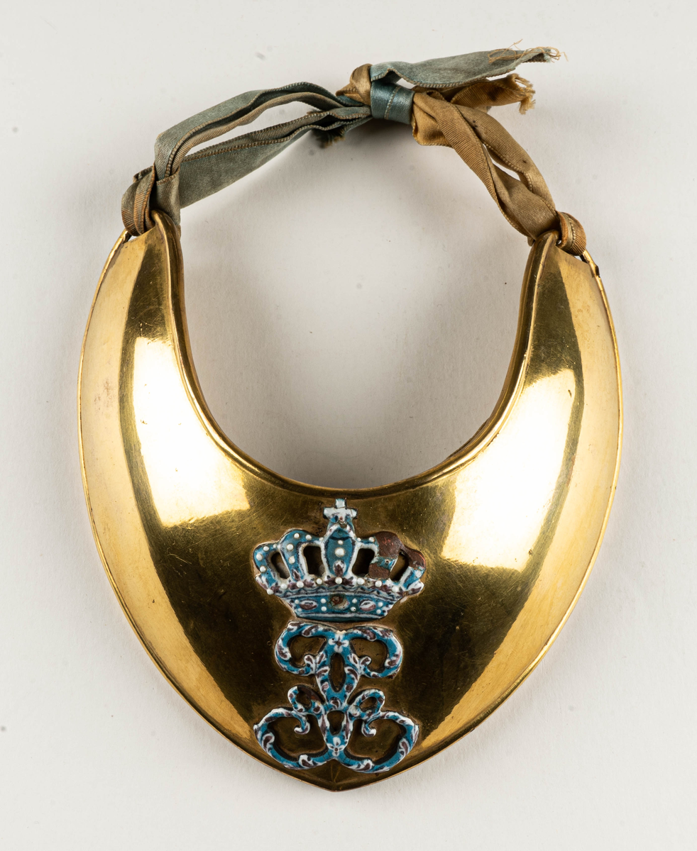 Dagofficersbricka, förgylld. Har tillhört kapten Th. Nordenadler, Högbo, Gästrikland.  Med Gustav III:s namnchiffer i ljusblå emalj. Dagofficersbrickan ingår i Gustav III:s uniform m/1779, för kaptener / kompanichefer för infanteriet.