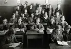 Undervisning i Nisbethska skolan, klass IV B, 1923. Flickor som sitter vid skolbänkar i en skolsal. Några står upp längre bak.