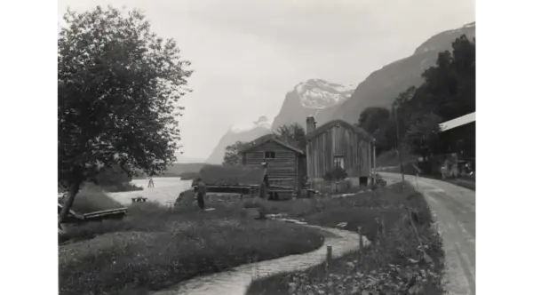 Gårdstun ved elva Driva med fjell i bakgrunnen, en vei går gjennom tunet.