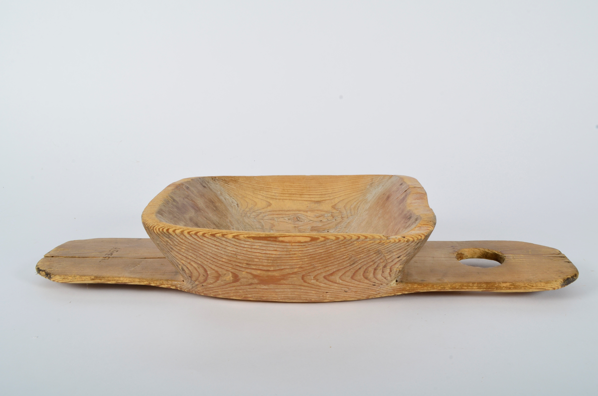 Melkesil av gran. Utskåret i ett stykke. To handtak, det ene med gjennombrudt hull. Selve silen - form som et trau - hullet i midten - form som et avrundet kryss med like armer. Litt sprukket ved. (Silhår mangler.)
