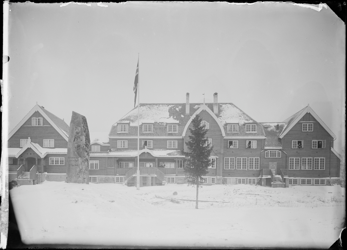 Elever henger i vinduene på Eidsvoll folkehøgskole. Tekst på baksiden: Folkehøeiskolen. Antakelig fotografert rundt 1908.