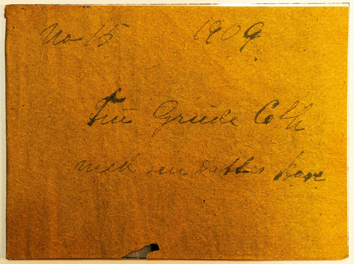 Portrett av mor og datter ved peisen. Tekst på baksiden: Fru Grude Coth med sin datter Aase, 1909.