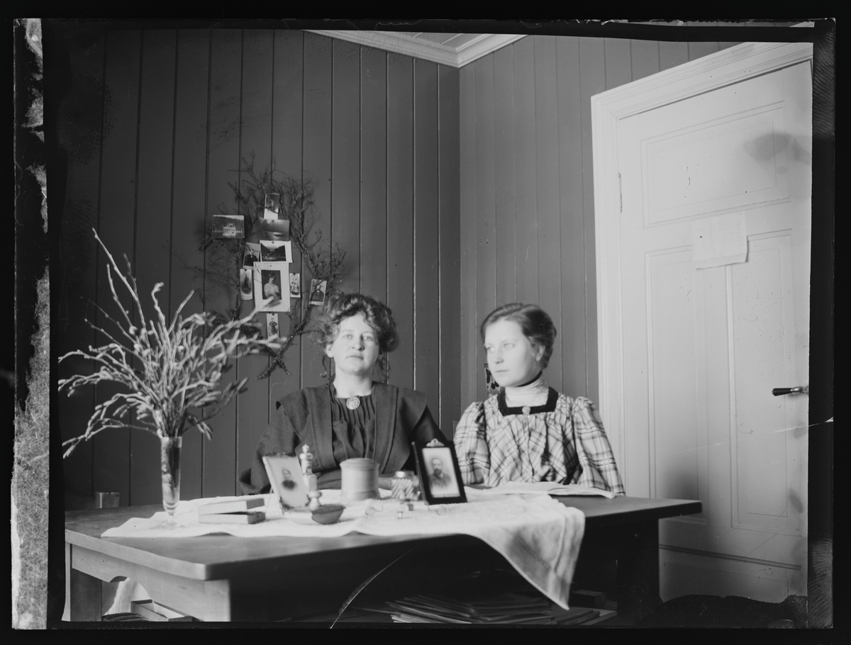 Portrett av to kvinner bak en skrivepult i et av folkehøgskolens soveværelser. Antatt elever ved Eidsvoll Folkehøgskole fotografert i 1909.

På konvolutt "Frk. Margit Blekastad og Dagny Fosberg, 473, 1909."
