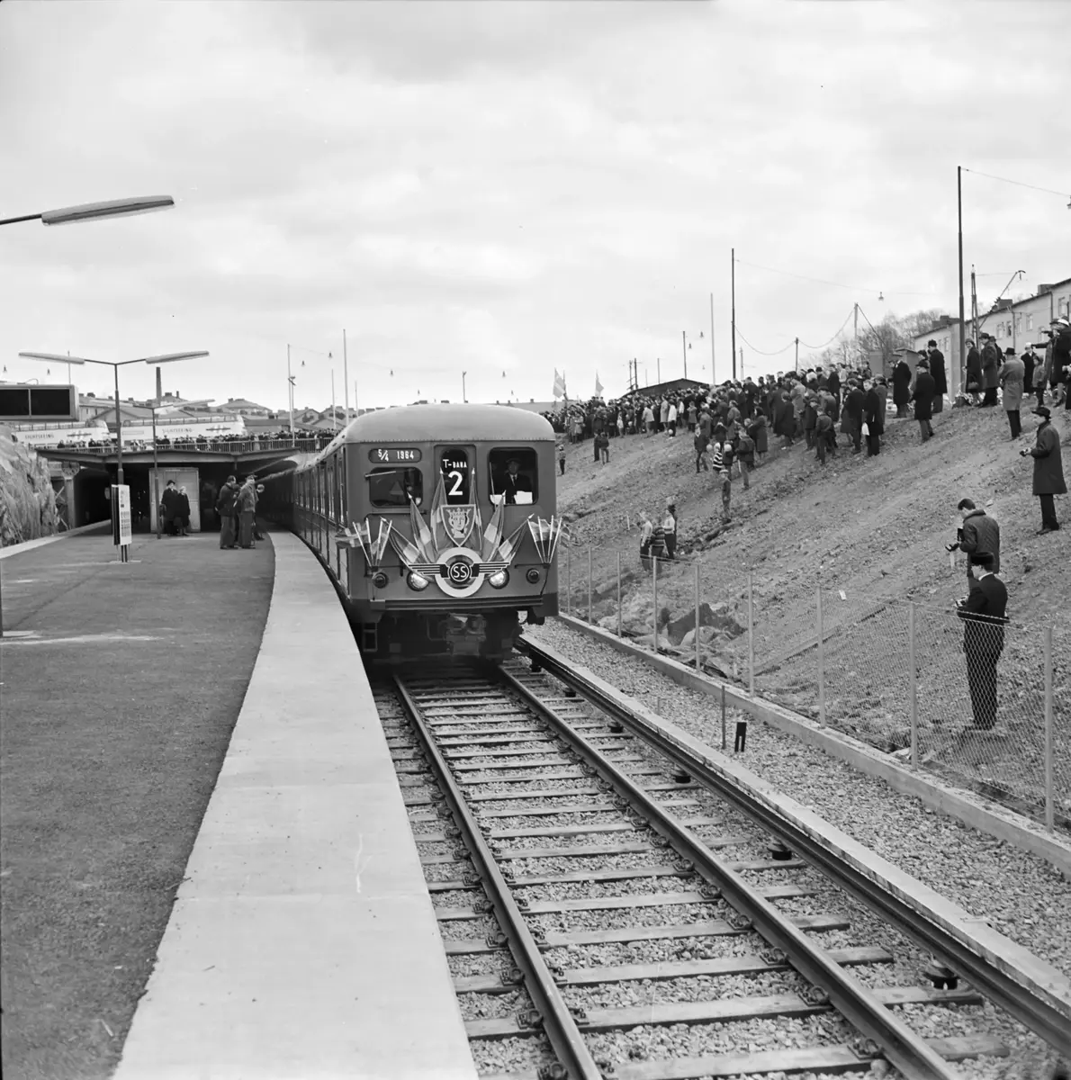 Tunnelbana 2, eller Röda linjen som vi säger idag, invigdes 5/4 1964. Invigning skedde vid Mariatorget och sedan körde invigningstågen först till Fruängen, återvände sedan till Liljeholmen och tog andra spåret till Örnsberg. Örnsberg var vid denna tid slutstation på linje 13. 