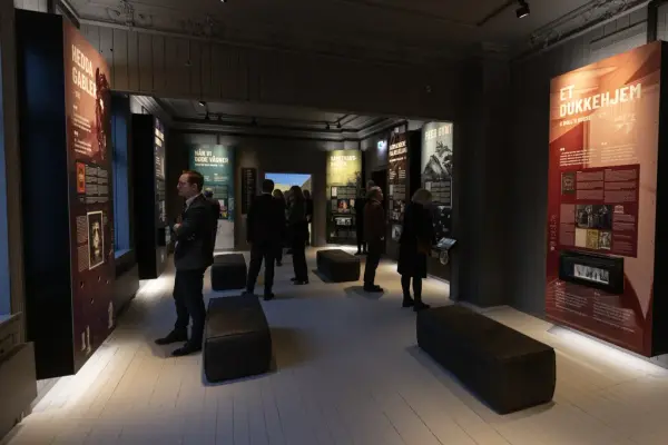 En gruppe mennesker studerer plansjer i utstillingen. 