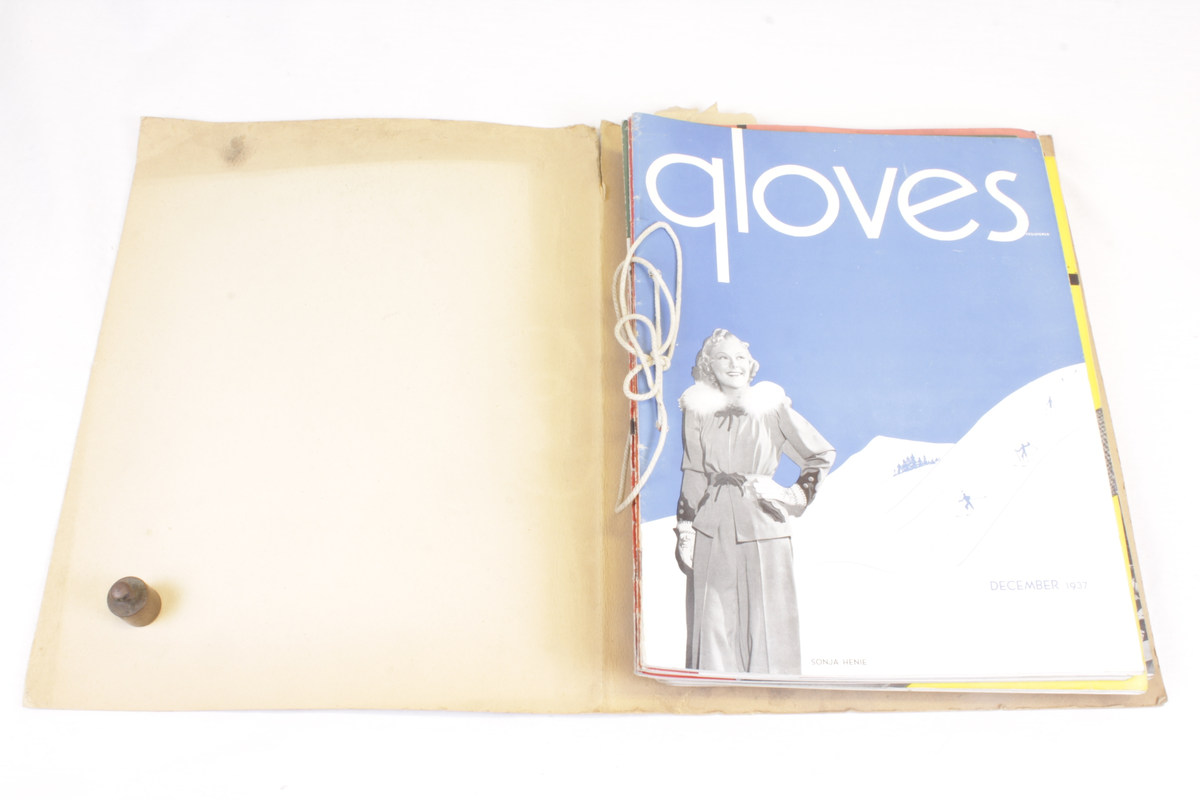 Årgang 1937 av bransjemagasinet "Gloves". Hjemmelaget "ringperm" som inneholder 13 blader som er gjennomhullet og festet sammen med tykk bomullstråd.