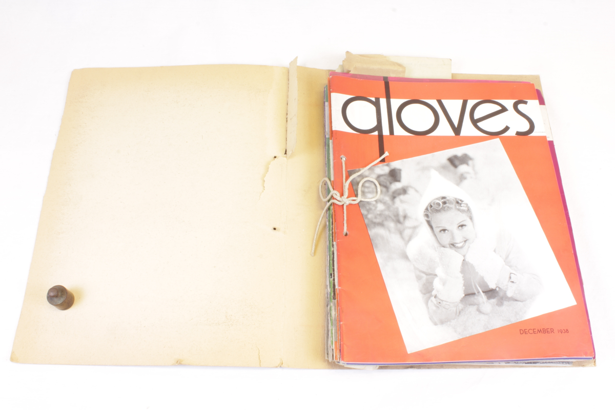 Årgang 1938 av bransjemagasinet "Gloves". Hjemmelaget "ringperm" som inneholder 14 blader som er gjennomhullet og festet sammen med tykk bomullstråd. Flere av bladene har papirbiter ilagt som bokmerke.