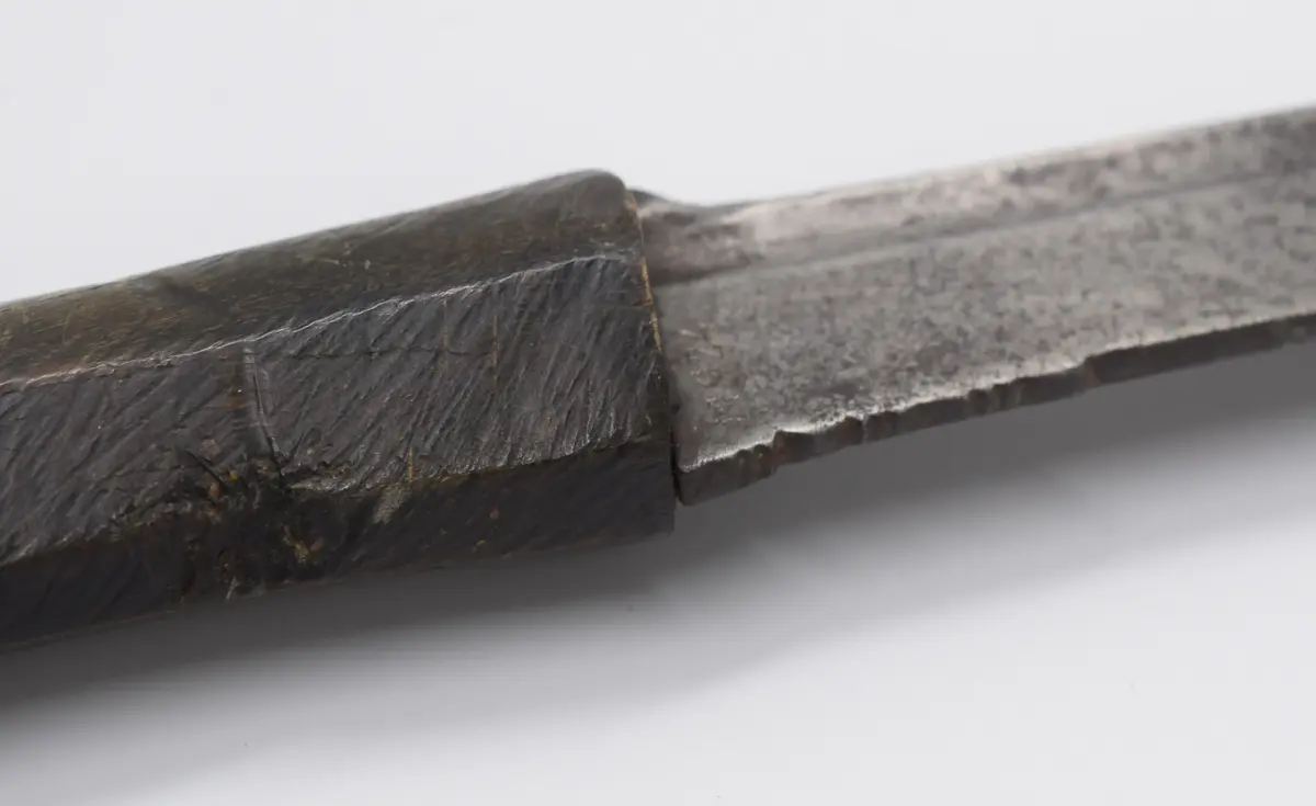  Malajsvärd,\"Klewang\". Huggvapen, handtag formad som en bockfot. Klinga av stål, med filade ränder framför fästet, på både rygg och eggsida. Fäste av något hårt träslag,eller ben, format som en klöv. Klingans spets avbruten ca 1cm.