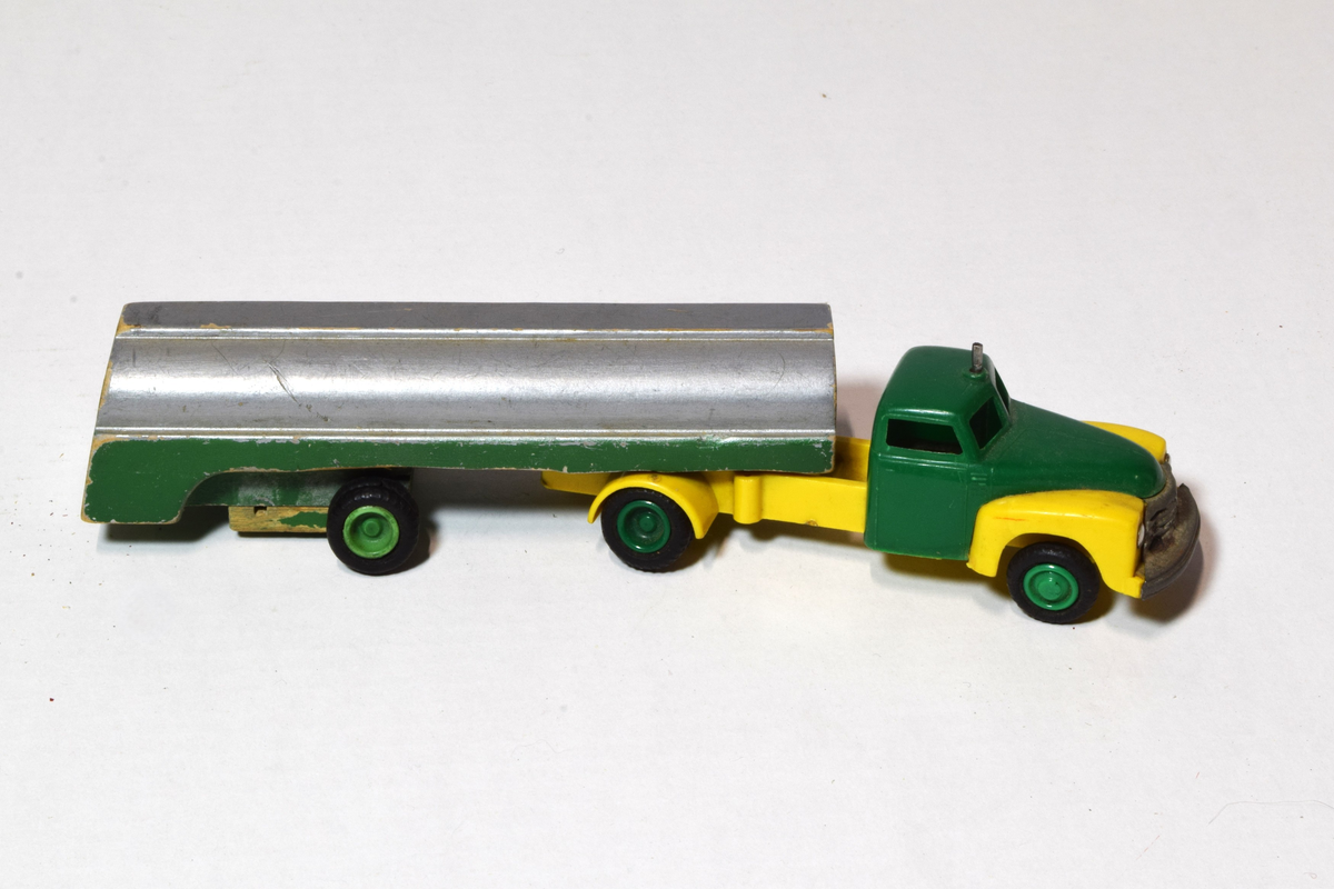 Fem lekekjøretøy av ulike størrelse, hvorav to lastebiler, en bil, en buss og en trailer. 3 trebilder og to av plast og metall.