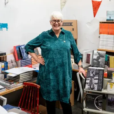 Kvinne står mellom masse fotobøker. 