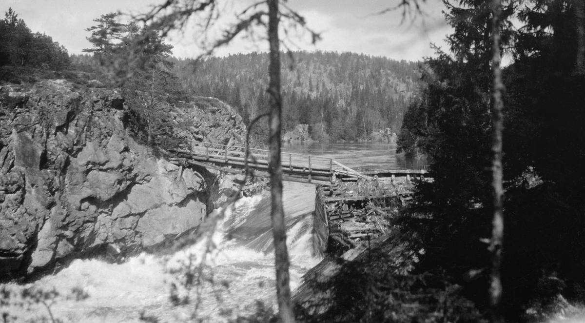 Den påbygde Sølvstudammen i Ågårdselva, fotografert under vårflommen i 1931. Bildet er tatt fra en bergkrent på sørsida av vassdraget, med kameraet vendt skrått mot dammen og strømretningen. Dammen var en forbygning av tømmer og planker (jfr. SJF.1989-04503, SJF.1989-04504 og SJF.1989-04505), som da dette fotografiet ble tatt var oversvømt av hurtigstrømmende vann. Over fossen og dammen lå det ei bjelkebru, lagd av rundtømmer, med rekkverk på den ene sida. Brua lå an mot en bergnabb på nordsida av vassdraget og mot et steinfylt tømmerkistekar med plankekledning på motstrøms side i den søndre enden. 

Ågårdselva er en del av Glommas vestre løp gjennom daværende Tune kommune i Østfold. Denne elvesrekningen er cirka fem og en halv kilometer lang og renner fra den nordvestre enden av Isnesfjorden (Vestvannet) sørvestover gjennem berglendt terreng mot innsjøen Visterflo. Høydeforskjellen mellom Isnesfjorden og Visterflo er på bortimot 25 meter. Ågårdselva har tre fossefall, det øverste her ved Sølvstu, deretter ved Valbrekke og nederst ved Solli. Denne elvestrekningen ble ikke brukt som fløtingsled lenger da dette fotografiet ble tatt. I perioden 1906-1908 bygde nemlig Fredrikstad Tømmerdirektion i bruk en tømmertunnel gjennom berget fra Svartdal (fra da av også kalt «Toppen») ved Isnesfjorden til Eidet ved Mingevannet. I årene som fulgte ebbet virksomheten ved det en gang så store Sanne og Solli Bruk ut. Likevel hadde man sannsynligvis startet diskusjonen om bygginga av en ny Sølvstudam. Selskapene Borregaards og Hafslunds hadde nemlig gjort inngrep i Glommas østre løp, hovedløpet, som i lavvannsperioder gjorde det svært vanskelig å få tømmer som skulle til bedrifter nedenfor Sarpsfossen via Mingevannet, Isnesfjorden og den nevnte tømmertunnelen til Eidet gjennom det ovenforliggende trange sundet ved Trøsken. Dette forsøkte man å løse ved å heve vannspeilet i Isnesfjorden med en dam som skulle plasseres 10-15 meter ovenfor den eksisterende dammen ved Sølvstufossen.