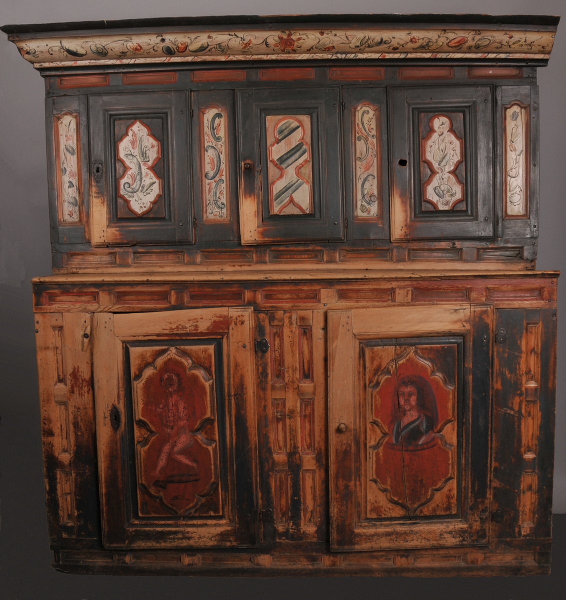 Øvre del har tre små skåpdører med ei hylle i kvar del. Nedre del har to store skåpdører med to hyller i kvar del. Rosemålinga er i grønt, raudt og kvitt. Kronelista er rosemåla på kvit botn. På venstre dørblad nede er det måla ein dansande figur og på høgre dørblad nede er det eit mannshovud. 