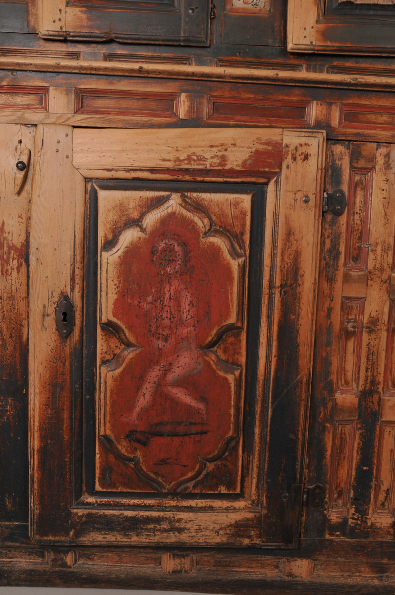 Øvre del har tre små skåpdører med ei hylle i kvar del. Nedre del har to store skåpdører med to hyller i kvar del. Rosemålinga er i grønt, raudt og kvitt. Kronelista er rosemåla på kvit botn. På venstre dørblad nede er det måla ein dansande figur og på høgre dørblad nede er det eit mannshovud. 