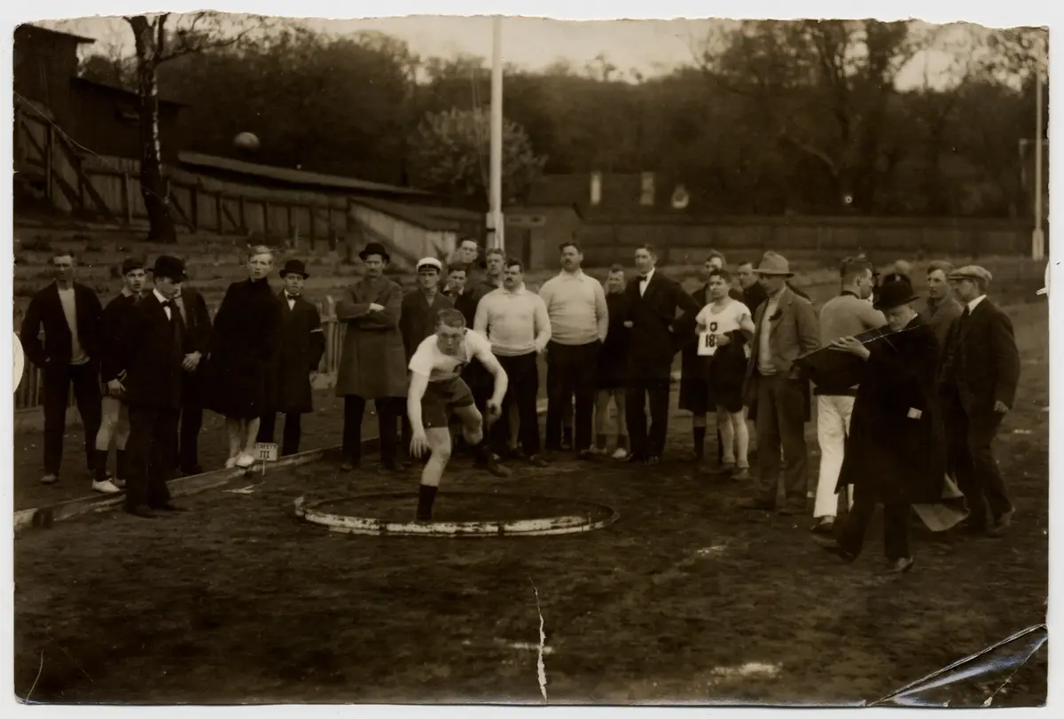 En kulstötare i aktion. Konkurrenter, funktionärer, 1910-talet.   Walhalla Idrottsplats.