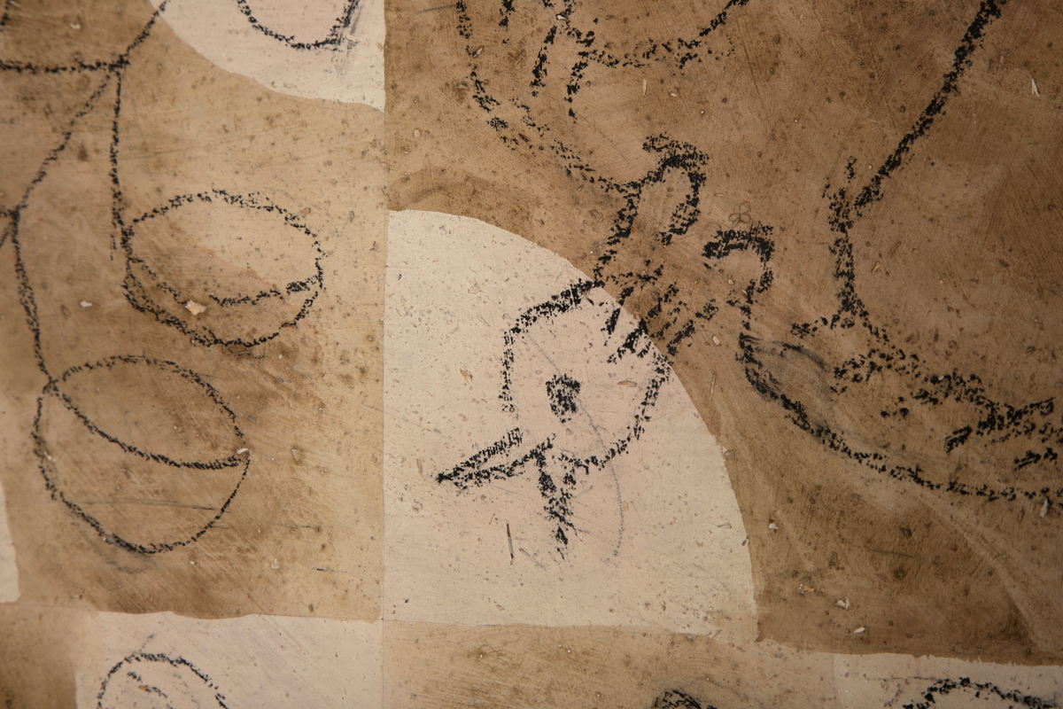 Utkast til tapet "Leik", malt og tegnet i seks ruter på beigefarget papir. Rutene har et brunt bølgeformet mønster midt på. Fire av rutene har grener med blader tegnet i kontur diagonalt over flaten, i to av rutene er det tegnet en fugl i flukt.