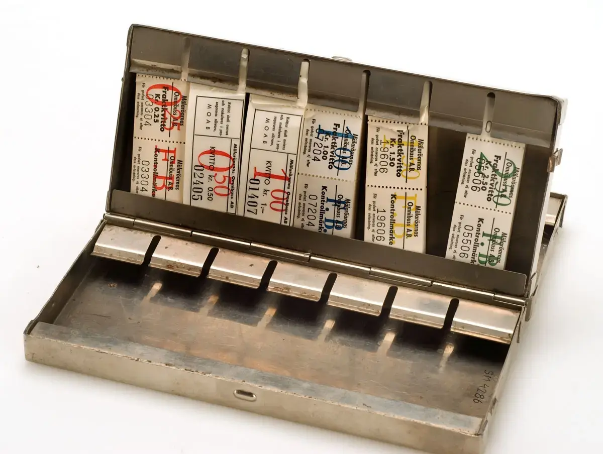 Biljettlåda från Mälaröarnas Omnibuss AB. För små blockbiljetter. Plats finns för 21 biljettblock i 3 fack. Innehåller följande biljetter:
MOAB, kvitto 50 öre, block med ursprungligen 200 bj
MOAB, kvitto 1 kr, block med ursprungligen 200 bj
MOAB, kvitto  25 öre. 1 kr,  1,50, 2,50 (fraktmärken)

MOAB