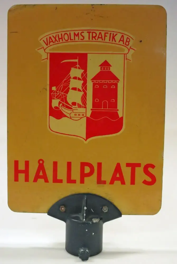 Gul tavla i glasfiberarmerad plast med röd text. Vaxholms Trafikaktiebolags logga samt texten HÅLLPLATS. Försedd med stolpfäste.

Bolag: Vaxholms Trafik AB
