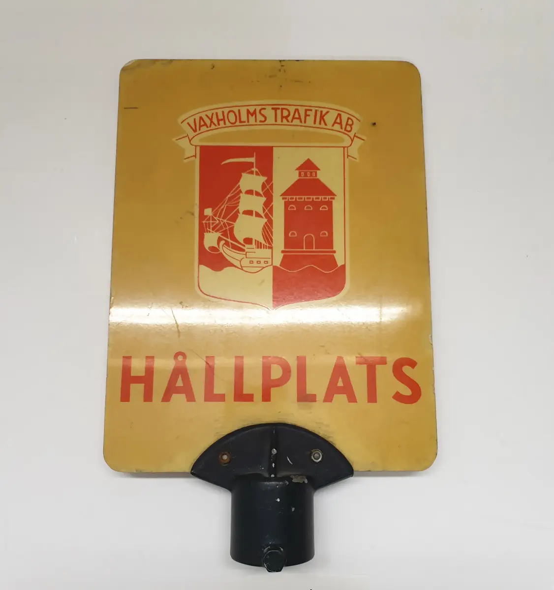 Gul tavla i glasfiberarmerad plast med röd text. Vaxholms Trafikaktiebolags logga samt texten HÅLLPLATS. Försedd med stolpfäste.

Bolag: Vaxholms Trafik AB