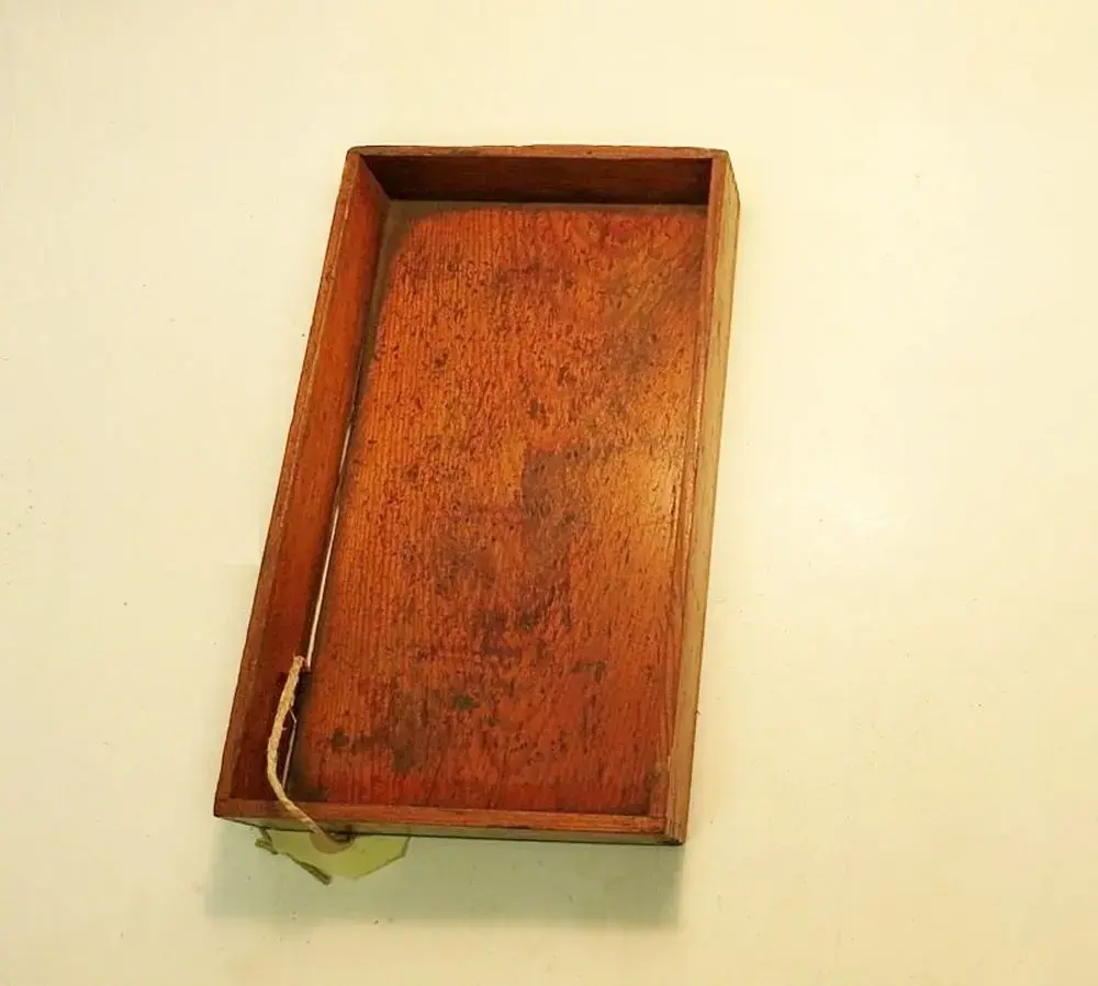Liten öppen trälåda (22x12,8x3 cm) på vars baksida det står skrivet "SNS AB"