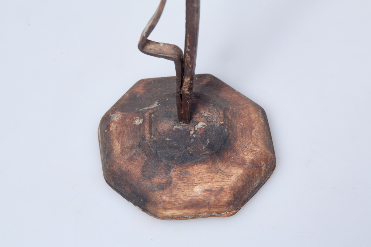 Foten av tre har syv kanter. Holderen er av jern og lyset står i en jernring.