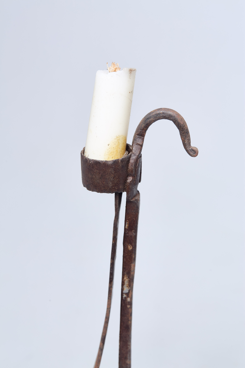 Foten av tre har syv kanter. Holderen er av jern og lyset står i en jernring.