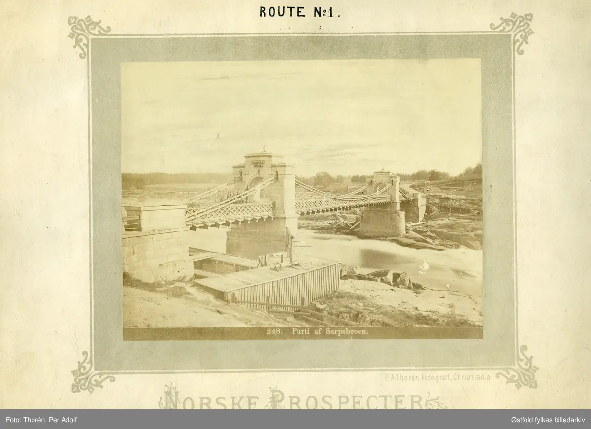 Sarpsbrua og Sarpsfossen i Sarpsborg, innviet 1854. Fotografert før jernbanebrua blei anlagt, Smaalensbanen ble vedatt bygd i 1873, og var i vanlig drift fra 1879.
NORSKE PROSPECTER
Route No 1.
248. Parti av Sarpsbroen.