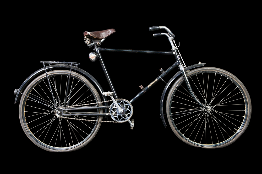 Cykel av stålrör. Diamond-ram utan bakstag, med dubbel bakgaffel. Spiralfjädrad terrysadel av läder. Styrhandtag celluloidklädda, svarta. Ringklocka med ett eklöv och ett ollon inom var sin sexkantig ram, samt namnet "PHÄNOMEN" i relief. Handbroms verkande på framdäckets ovansida. Lykthållare. Cylindrisk vertygslåda av plåt på sadelröret. Pakethållare på fyra stag, som konvergerar i bakgaffeländarna. Fjäderklämmor för pump på nedre ramröret. Omfångsrik vevlagerhylsa. Kattöga. Styre och framgaffelkrona förkromade. I övrigt svart lackering med smala, gula och blå linjer och bred gul rand i fälgarnas mitt. På styrrörets framsida runt, vitt fält med text: "PHÄNOMEN-WERKE GUSTAV HILLER A.G. ZITTAU" och i centrum sexkantigt, mörkblått fält med: "PHÄNOMEN" i guldskrift. På vertygslådans lock: "PHÄNOMEN SCHWINGRAD" i rött, blått och vitt.