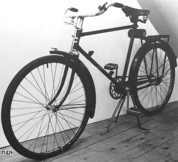 Cykel av stålrör. Diamond-ram utan bakstag, med dubbel bakgaffel. Spiralfjädrad terrysadel av läder. Styrhandtag celluloidklädda, svarta. Ringklocka med ett eklöv och ett ollon inom var sin sexkantig ram, samt namnet "PHÄNOMEN" i relief. Handbroms verkande på framdäckets ovansida. Lykthållare. Cylindrisk vertygslåda av plåt på sadelröret. Pakethållare på fyra stag, som konvergerar i bakgaffeländarna. Fjäderklämmor för pump på nedre ramröret. Omfångsrik vevlagerhylsa. Kattöga. Styre och framgaffelkrona förkromade. I övrigt svart lackering med smala, gula och blå linjer och bred gul rand i fälgarnas mitt. På styrrörets framsida runt, vitt fält med text: "PHÄNOMEN-WERKE GUSTAV HILLER A.G. ZITTAU" och i centrum sexkantigt, mörkblått fält med: "PHÄNOMEN" i guldskrift. På vertygslådans lock: "PHÄNOMEN SCHWINGRAD" i rött, blått och vitt.