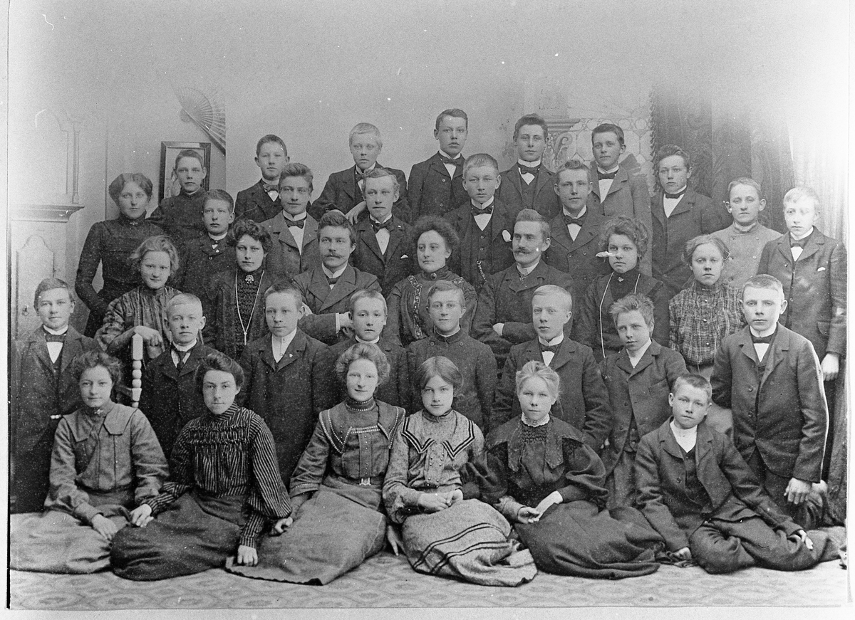 Klassebilde fra Toten Amtskole ca. 1906. Nr. en fra venstre i tredje rekke er Olga Pauline Alfstad, nr. tre lærer Boye Høverstad. Nr. to fra venstre i første rekke Karen Evenrud (gift Fosmo). Nr. tre fra venstre i andre rekke er Helge Lund. De øvrige er ukjente.