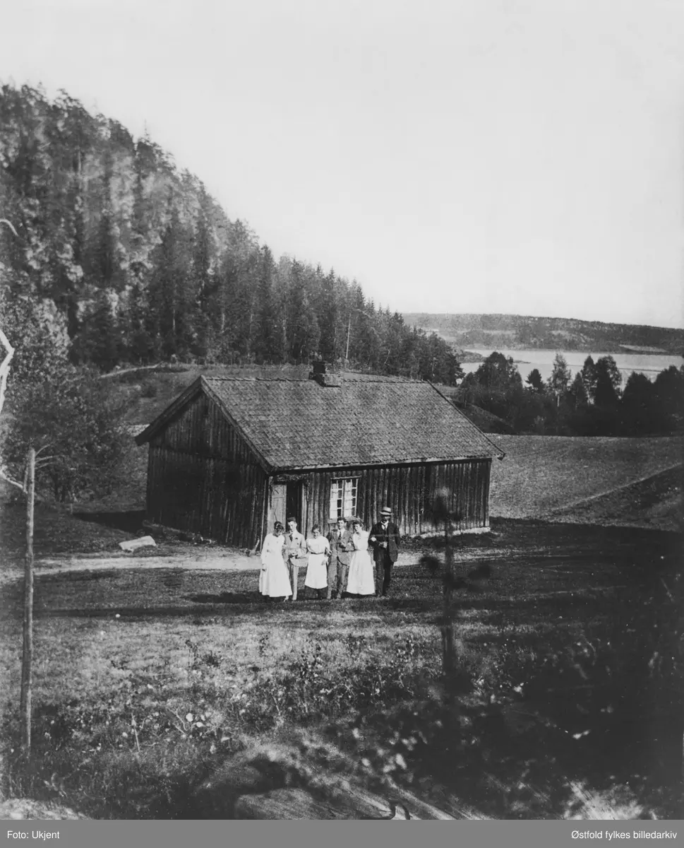 Grøtet ved Vestvannet., Tune Arbeiderbolig med familien oppstilt på utsiden. Vestvannet i bakgrunnen. Andre bilde er utsnitt av gruppen foran huset.
