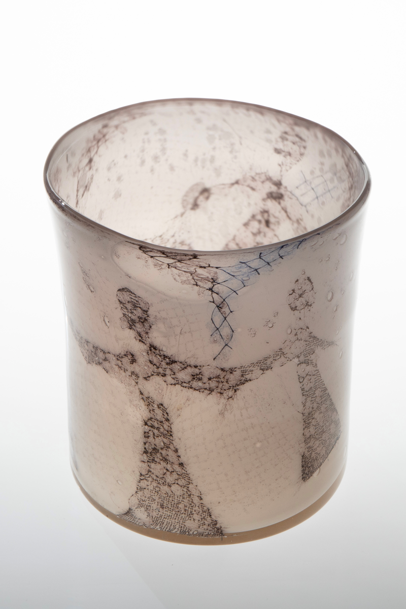 Høyreist ovalformet vase i grårosa glass med innlagt dekor av metallnett. Dekoren fremstiller stiliserte kvinnefigurer i en dansende bevegelse. Øvre del er svakt konisk og har en ujevn formet munningsrand.