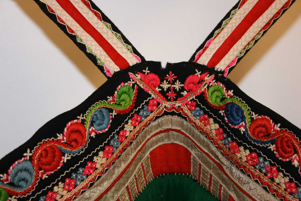 Svart vadmålsstakk med selar og broderi.