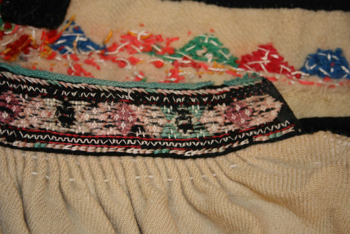 Kvit vadmålsstakk med selar og broderi.