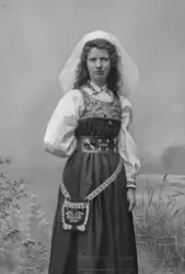 Porträtt av fotograf Ester Läckgren i folkdräkt. 
Text på ba