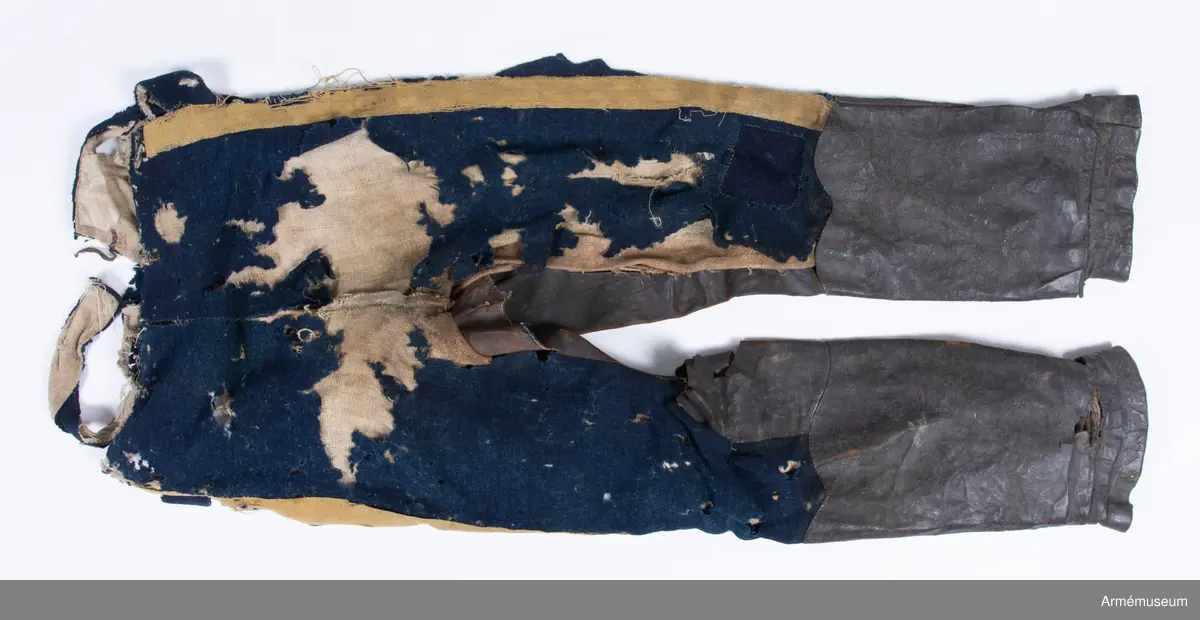 Blå ridbyxor med gula revärer och skinnskodda ben och byxbak.

Byxorna är sydda av ett ganska tunt blått kommisskläde, och är helfodrade med oblekt linne- eller hampalärft.
Modellen är konstruerad med två fram- och två bakstycken, och har hel lucka fram som har knäppts mot en gördel eller linning. Luckan har 5 knapphål fram, varav tre har knäppts mot gördeln. I luckans sidor upptill sitter två spänntampar för knäppning bak i ryggslutet. I sömmen bak sitter en infälld kil för reglering av midjevidden, samt en hank av läder för upphängning.
I sidan har byxorna revärar av 4 cm breda gula redgarnsband.
Byxbenen är skodda med brunt skinn i en höjd av ca 36 cm nertill. Kanten är formad i två bågar fram och en spets bak. Skinnskoningen fortsätter på baksidan upp på insidan av låren och i byxbaken.
Byxorna är mycket trasiga och malätna, och både yttertyg och foder har lagats ett flertal gånger under deras användningstid.
Samtliga knappar saknas förutom i höger byxben längst ner där det sitter rester av enkla skinnknappar i varje sida.

Märkt på insidan "LS No 2".