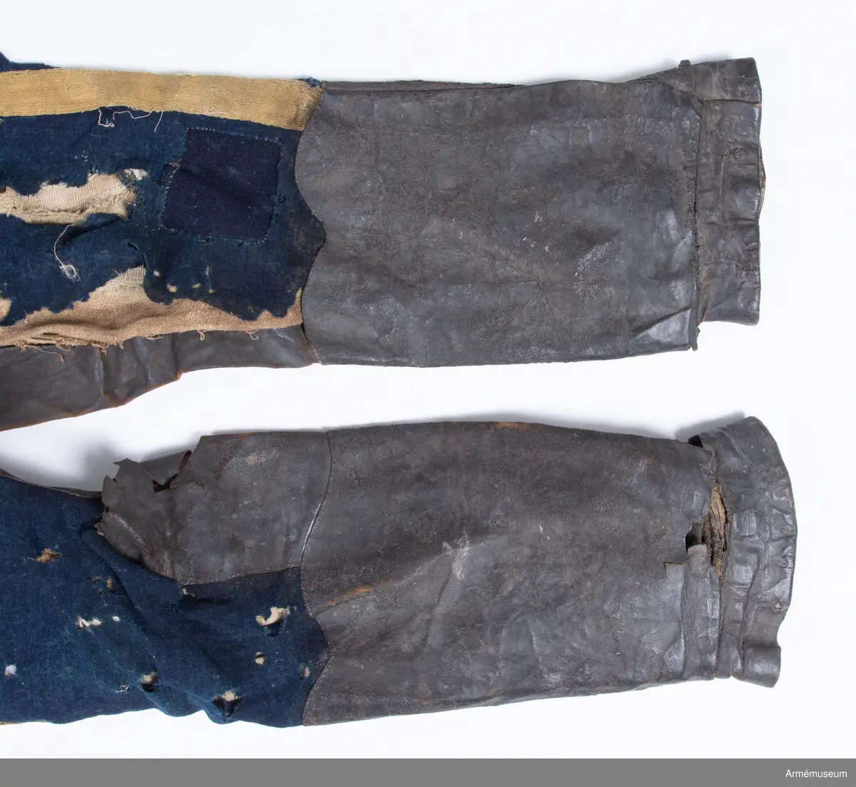 Blå ridbyxor med gula revärer och skinnskodda ben och byxbak.

Byxorna är sydda av ett ganska tunt blått kommisskläde, och är helfodrade med oblekt linne- eller hampalärft.
Modellen är konstruerad med två fram- och två bakstycken, och har hel lucka fram som har knäppts mot en gördel eller linning. Luckan har 5 knapphål fram, varav tre har knäppts mot gördeln. I luckans sidor upptill sitter två spänntampar för knäppning bak i ryggslutet. I sömmen bak sitter en infälld kil för reglering av midjevidden, samt en hank av läder för upphängning.
I sidan har byxorna revärar av 4 cm breda gula redgarnsband.
Byxbenen är skodda med brunt skinn i en höjd av ca 36 cm nertill. Kanten är formad i två bågar fram och en spets bak. Skinnskoningen fortsätter på baksidan upp på insidan av låren och i byxbaken.
Byxorna är mycket trasiga och malätna, och både yttertyg och foder har lagats ett flertal gånger under deras användningstid.
Samtliga knappar saknas förutom i höger byxben längst ner där det sitter rester av enkla skinnknappar i varje sida.

Märkt på insidan "LS No 2".