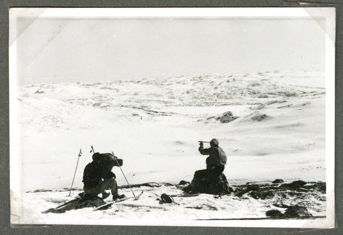 Personer på ski. Til høyre sitter en ung mann på stein og ser utover landskapet med en kikkert