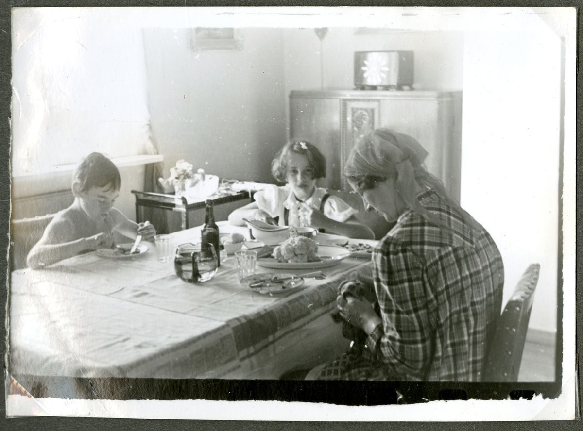 Becker familien sitter rundt bord. 

Fra høyre: Ivar Becker, hans søster Sonja Becker og deres mor Signe Becker