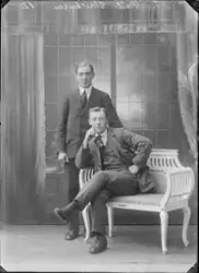 Portrettfoto. To menn oppstilt i fotostudio.